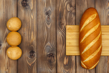 Loaf of bread, buns on a wooden background