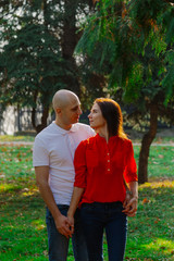 Happy lovers in the park at thuja in autumn sunny weather.