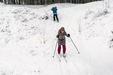 girl slides downhill on skis, and a boy climbs uphill
