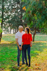 Fototapeta premium Szczęśliwi kochankowie w parku przy tui w jesienną słoneczną pogodę.