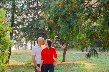 Obraz premium Happy lovers in the park at thuja in autumn sunny weather.