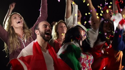 Football / Soccer fans or supporters celebrate with confetti falling. They jump and cheer. Super slow motion.