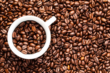 White cup with coffee beans on a background of coffee beans