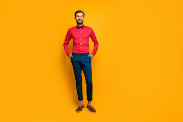 Full length photo of amazing macho man standing good mood friendly beaming smiling wear stylish red shirt with bow tie blue pants shoes isolated yellow color background