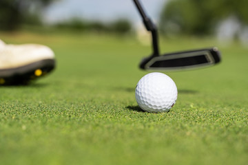 Golf ball and a person's shoes on a golf course