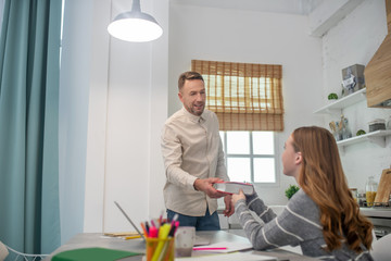 Short-haired bearded man giving a book to his student