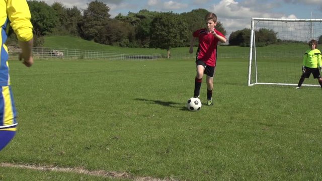 Boys / Children playing soccer / football outdoors on a sunny day. One child uses skill to get past his opponent. Slow motion - Stock Video Clip Footage