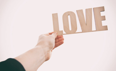 The wooden word LOVE in the woman's hand against the sunset