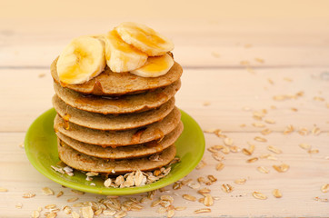 Breakfast oatmeal pancakes with banana and honey for a breakfast on light background closeup, selective focus