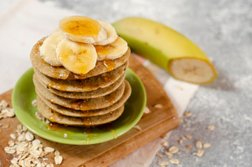 Breakfast oatmeal pancakes with banana and honey for a breakfast on light background closeup, selective focus