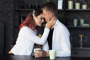 Young couple in love, a guy and a girl with pink hair in the kitchen