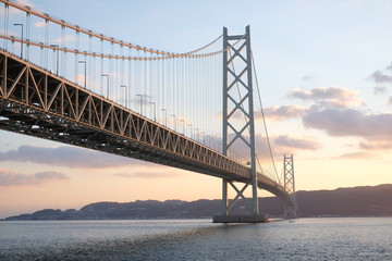 View Of Akashi Strait Bridge Over Sea Against Cloudy Sky At Sunset
