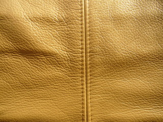 The texture of the skin close-up. Genuine haberdashery leather in gold color. Genuine Leather