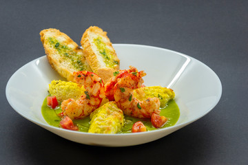 Garlic shrimp accompanied by green sauce and breads with butter and chopped parsley
