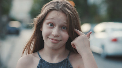 Close-up portrait of nice surprised little girl with long hair. Outdoors. Reaction to strange...