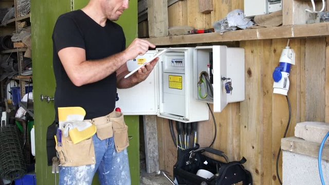 Electrician inspects Fuse box and is using a digital touchscreen tablet. Fusebox - Stock Video clip footage. 