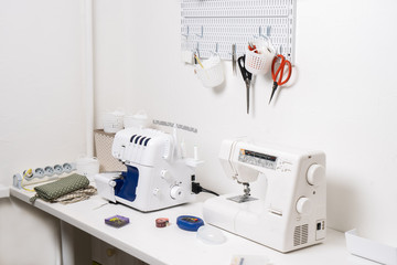 Workplace: White table with a sewing machine and an overlock for sewing.