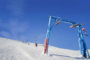 Fotobehang Ski lift going over the snowy mountain and paths from skies and snowboards. © luengo_ua