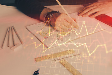 Double exposure of man's hands writing notes of stock market with forex chart.