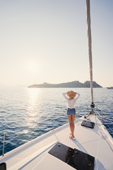 Luxury travel on the yacht. Young happy woman on boat deck sailing the sea. Yachting in Greece.