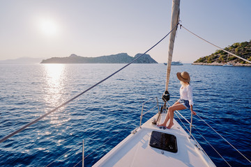 Luxury travel on the yacht. Young happy woman on boat deck sailing the sea. Yachting in Greece.