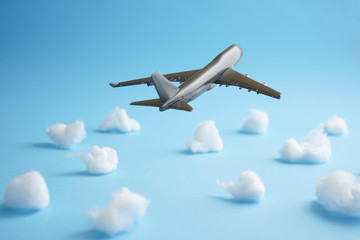 Travel concept an airborne airplane on blue background with cottons mimic flying on clear blue skies with partial clouds