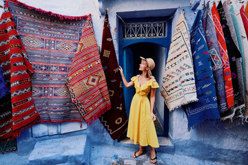 Voyage coloré par le Maroc. Jeune femme en robe jaune marchant dans la médina de la ville bleue de Chefchaouen.
