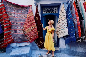 Papier Peint photo autocollant Maroc Voyage coloré par le Maroc. Jeune femme en robe jaune marchant dans la médina de la ville bleue de Chefchaouen.