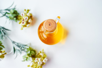 Bottle of natural oil with florals on white background.