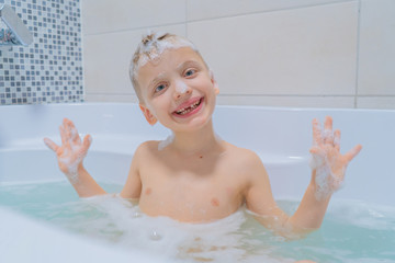 6-7 years old boy taking a bath, looking at the camera and smiling