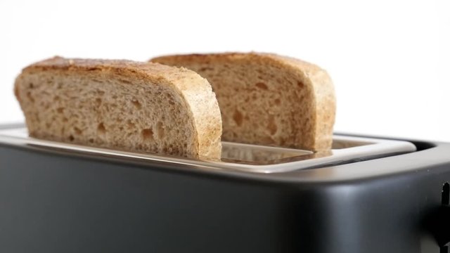 Two pieces of bread pop-up from black toaster slow-motion footage