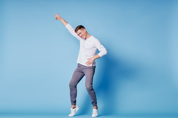 Colorful studio portrait of happy young man dancing against blue background.