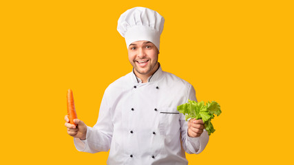 Professional Chef Holding Carrot And Salad Standing On Yellow Background