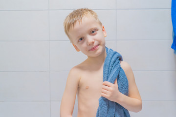 6-7 years old boy taking a bath, baby is standing with a towel and looking at the camera