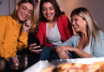 Three female friends chatting and making selfie at home.