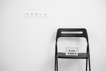 Girl power text on the lightbox. white wall and sockets. blsck chair