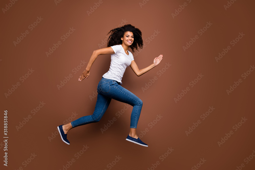 Poster Full size profile photo of amazing dark skin lady jumping high sports competitions rushing finish line winner mood wear casual white t-shirt jeans isolated brown color background