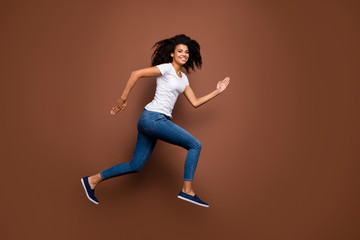 Fototapeta na wymiar Full size profile photo of amazing dark skin lady jumping high sports competitions rushing finish line winner mood wear casual white t-shirt jeans isolated brown color background