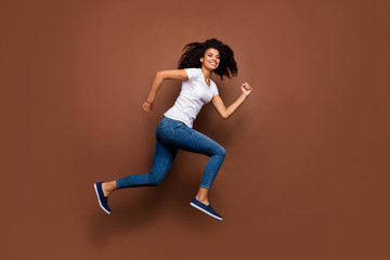 Fototapeta na wymiar Full length profile photo of funny dark skin lady jumping high sports competitions participant rushing finish line wear white t-shirt jeans isolated brown color background