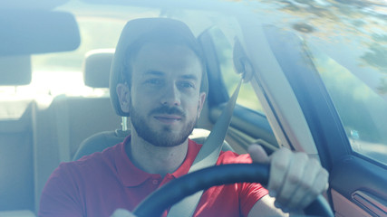 Young smiling man driving a car on a road trip sunset sunlight transport holiday happy adventure car short hair free time journey smiling summer travel slow motion