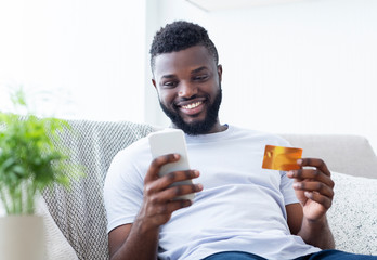 African american man holding credit card and cellphone