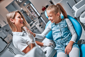 Creative professional dentist giving her little patient a high five