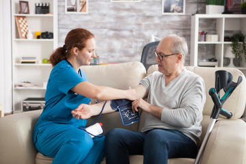Young doctor in nursing home taking digital blood pressure