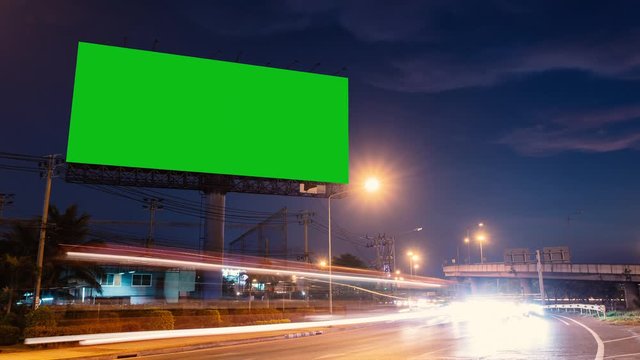 4k - Advertising billboard green screen on sidelines of expressway with traffic at evening, time lapse.