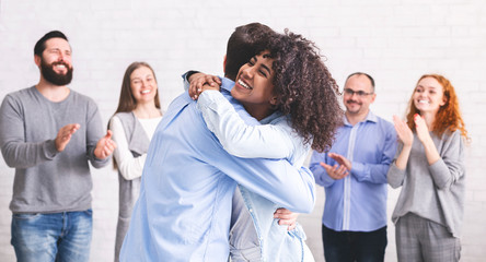 Diverse people hugging after successful workshop or seminar