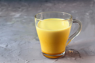 Hot healthy indian golden milk with diferent spices (cardamon, anice, cinnamon, ginger) on a gray grunge background
