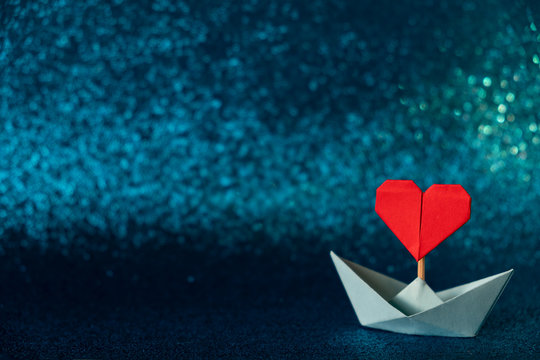 Valentine's day greeting card. Origami boat with heart flag on glitter blue background Romantic, Valentines day concept with space for text.