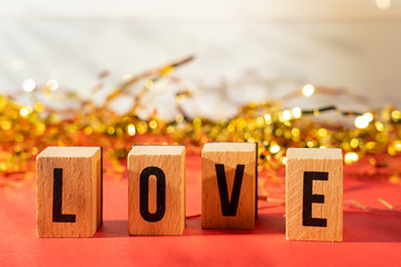 Letters with the message love, red background and gold confetti.