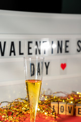 Bright Valentine's Day sign, champagne glasse and gold confetti.