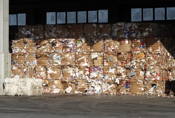 Lined up stacks of cardboard and waste paper   in a recycling plant storage.